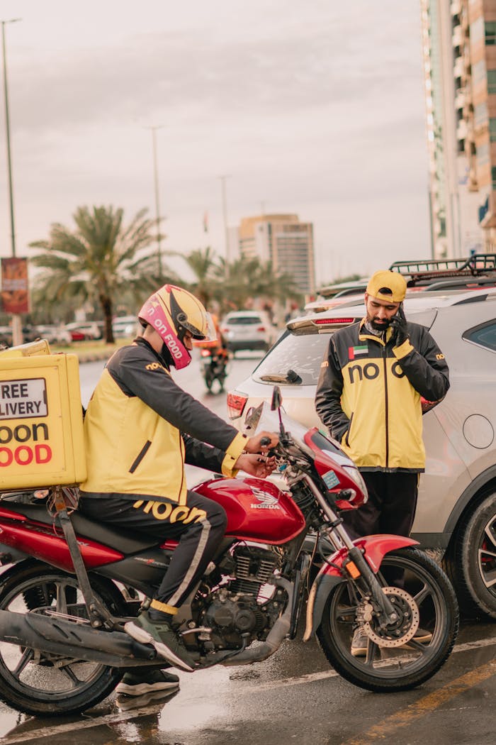 Two delivery service men on a motorbike in Dubai with 'noon' branding, highlighting urban transport efficiency.