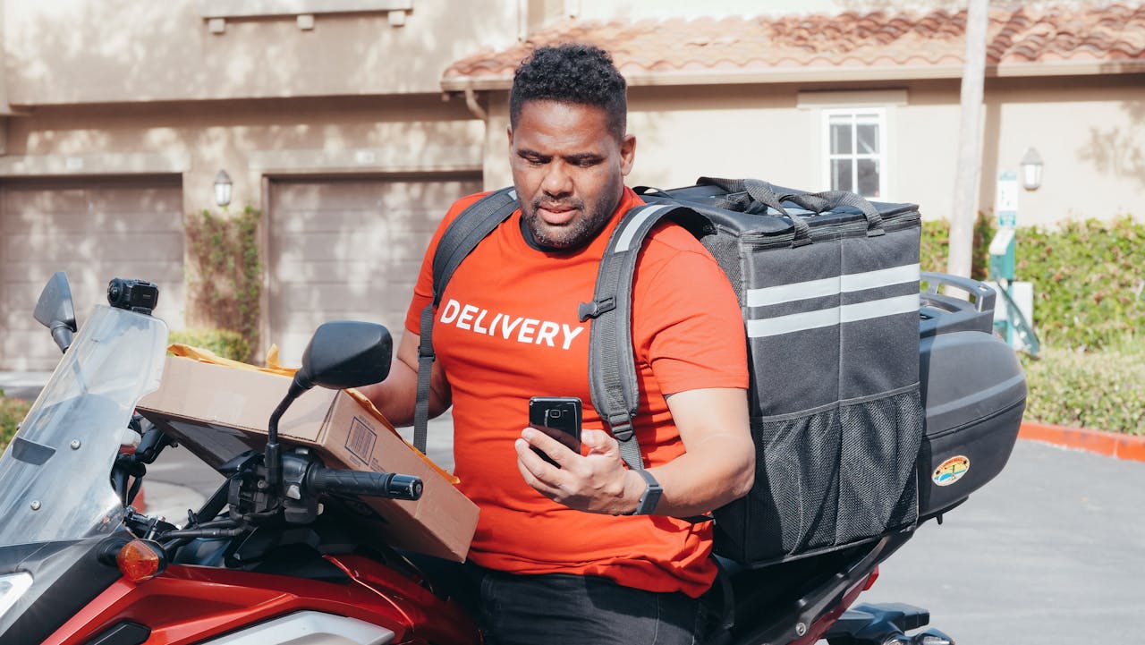 Courier on a motorcycle with a box and phone, showcasing efficient delivery service.