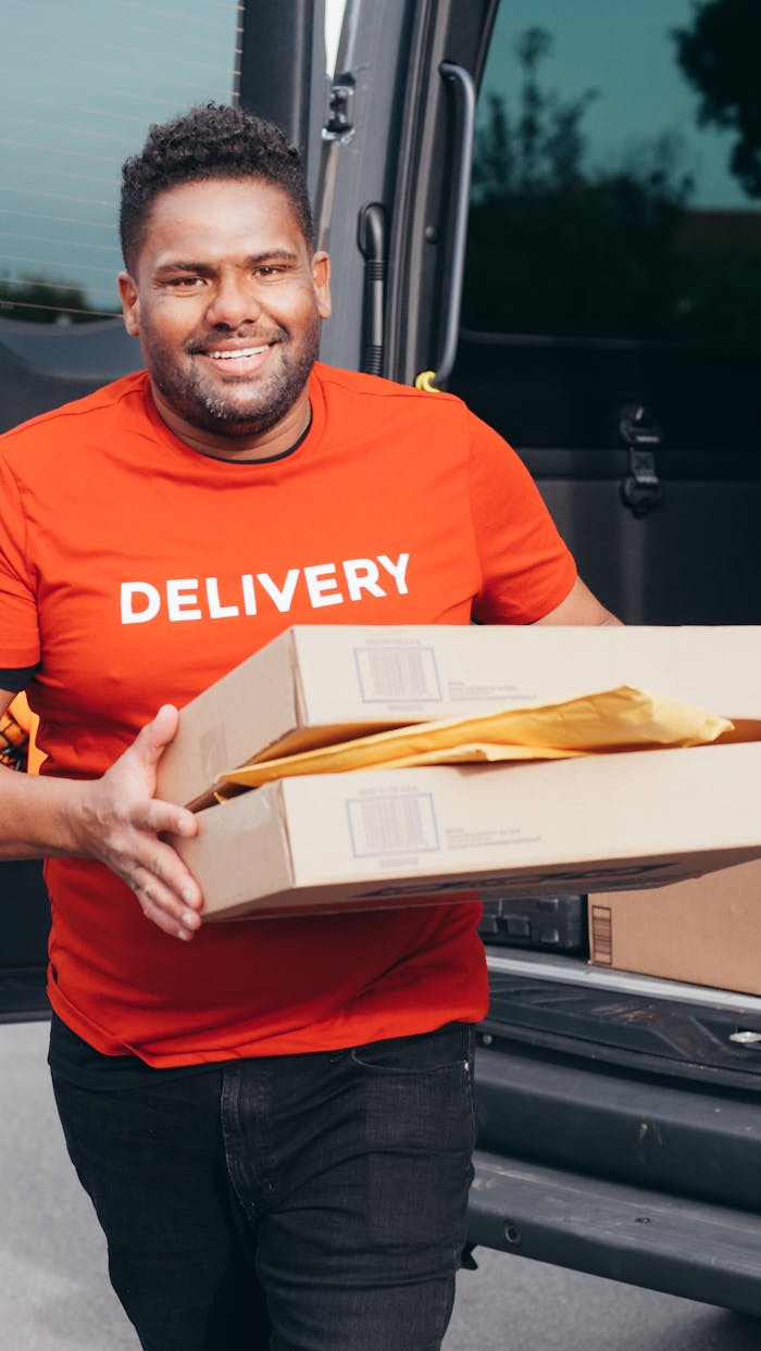 Friendly courier in a red shirt delivering packages from a van, showcasing efficient delivery service.